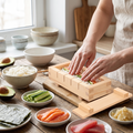 Hands pressing sushi rice in wooden sushi mold